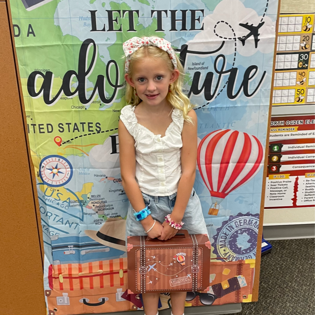 Student standing in front of a banner that says Let the Adventure Begin.