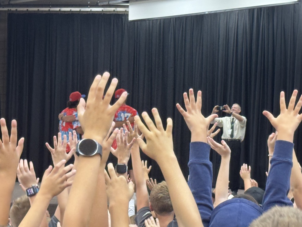 students hands in the air as the raptors players take a selfie with the whole school