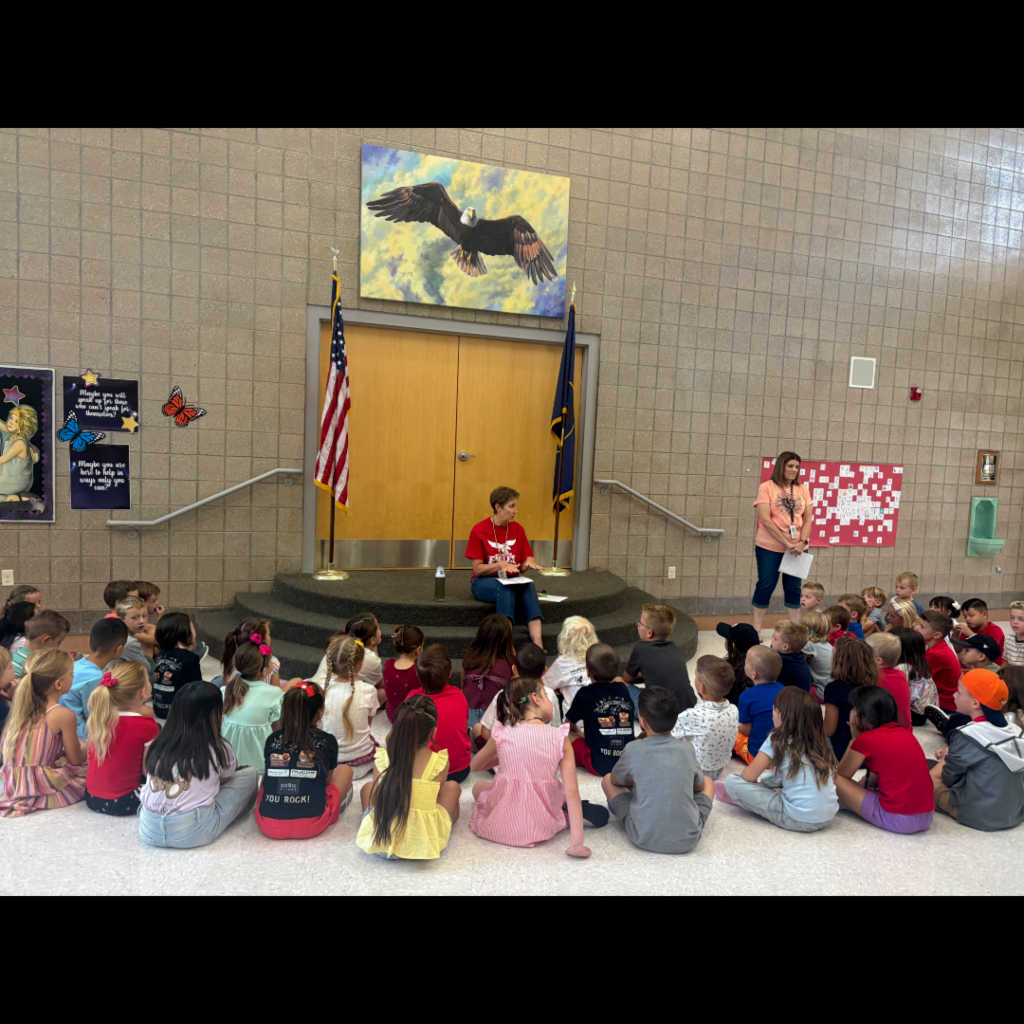 Students sitting on the floor listening to the rules and procedures of the school.