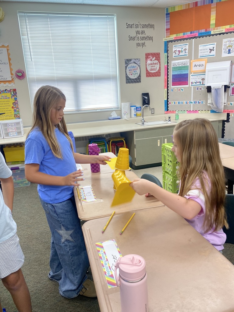 girls doing an experiment with cups and paper