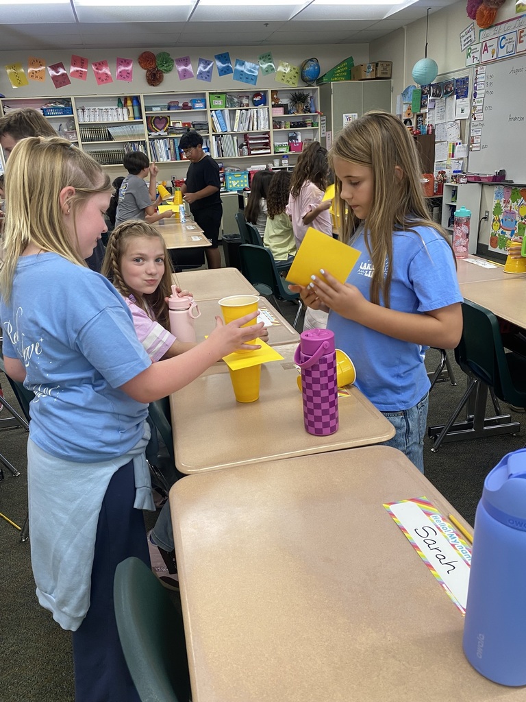 girls doing an experiment with cups and paper