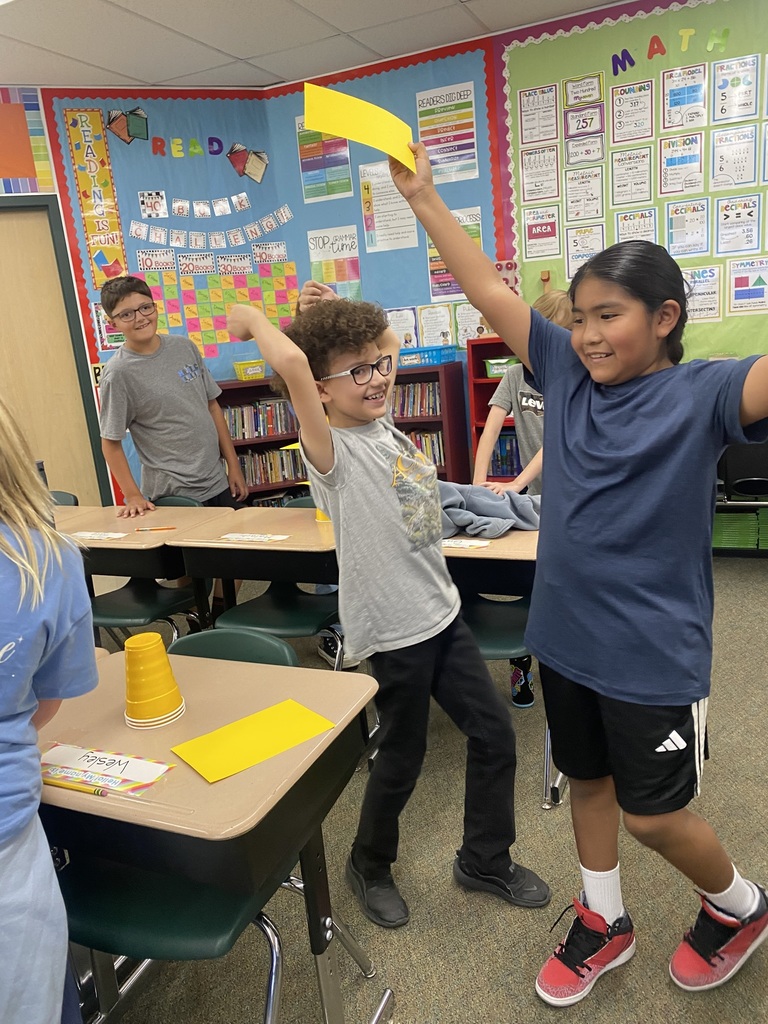 Kids raising their hands in the air because they completed the cup experiment