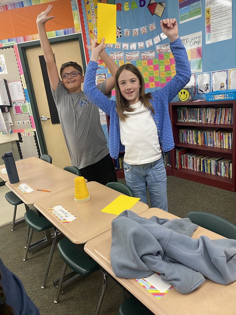 Kids raising their hands in the air because they completed the cup experiment