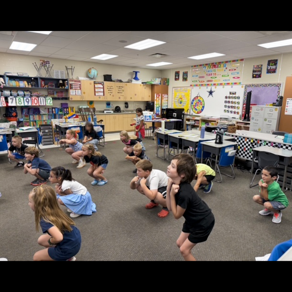 A class of students squating in their classroom.