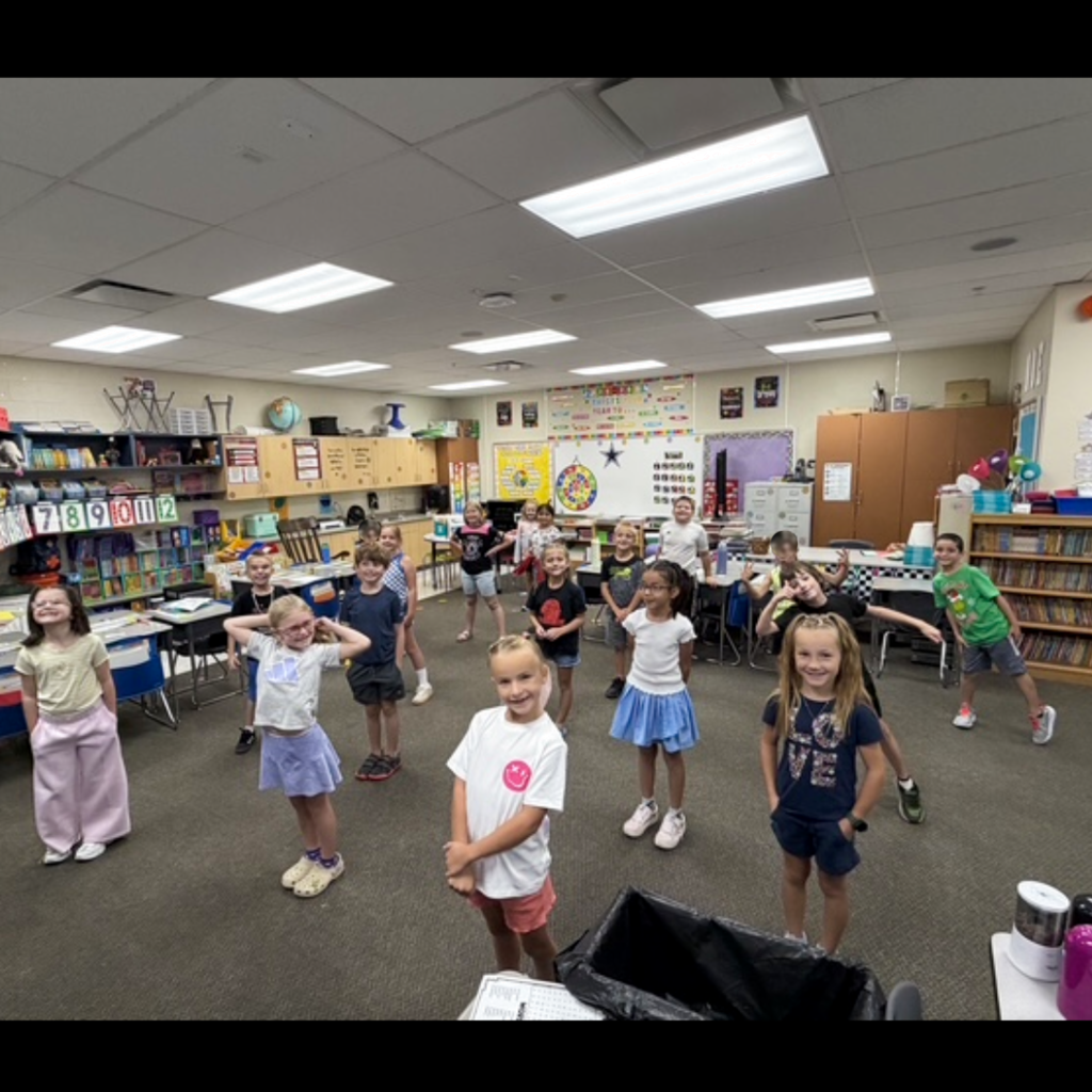 A class of students standing in their classroom.