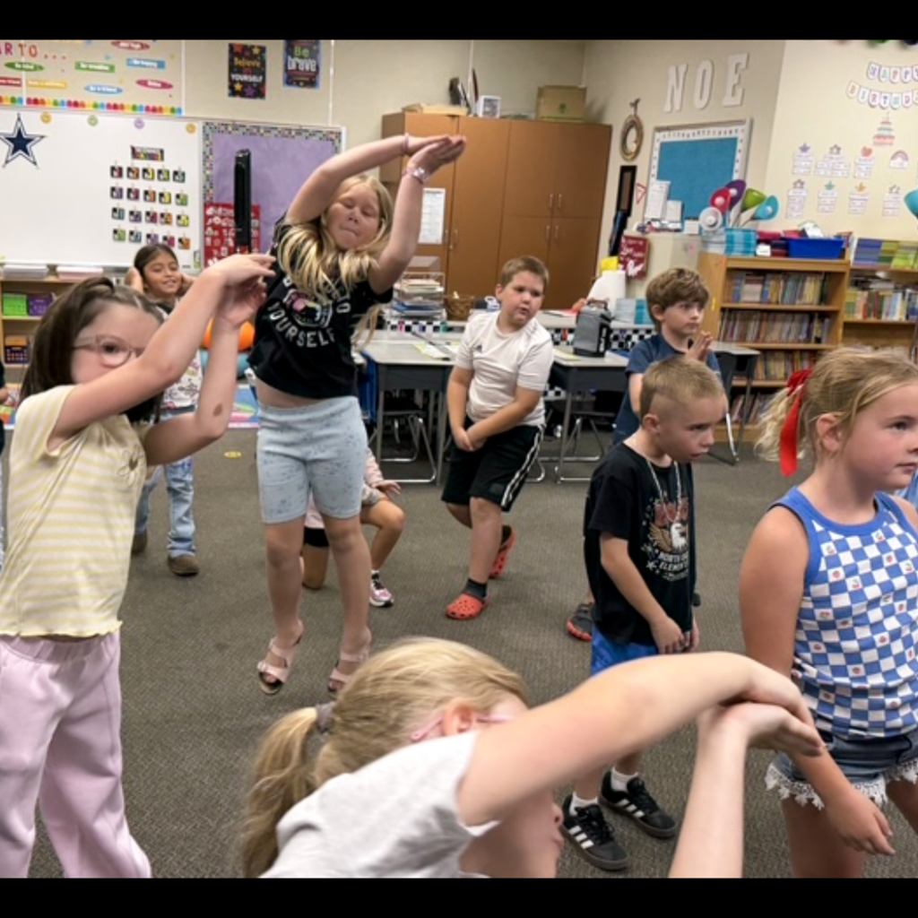 A class of students dancing in their classroom.