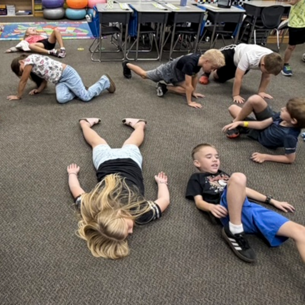 A class of students laying on the floor in their classroom.