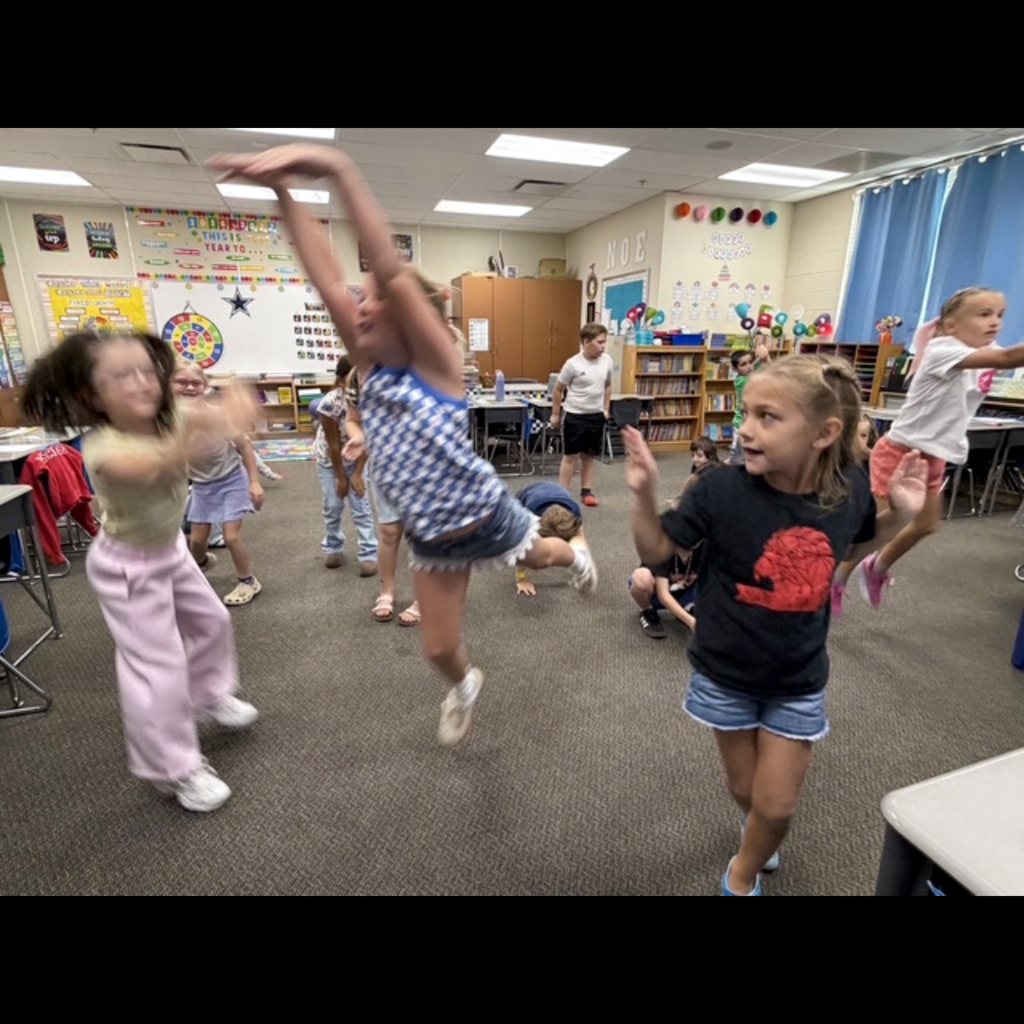 A class of students dancing in their classroom.