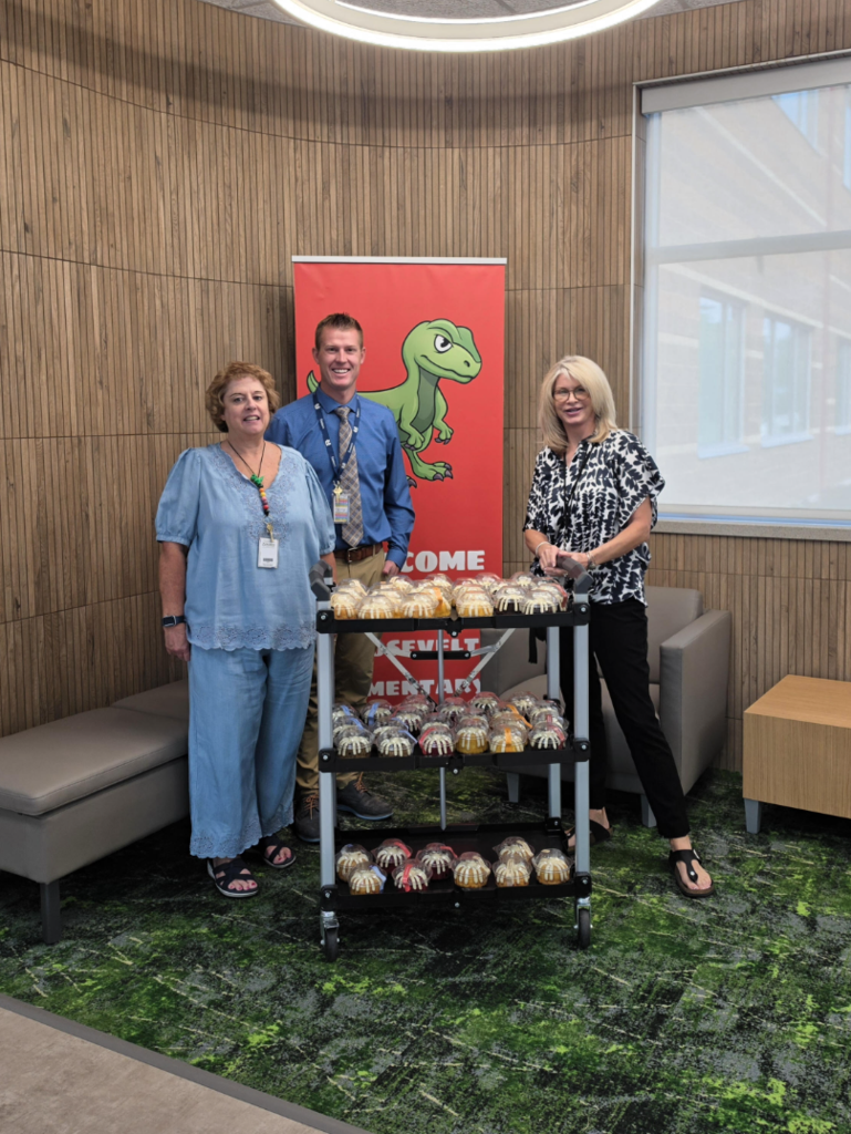 three teachers standing in front of a roosevelt banner with the donated bunt cakes