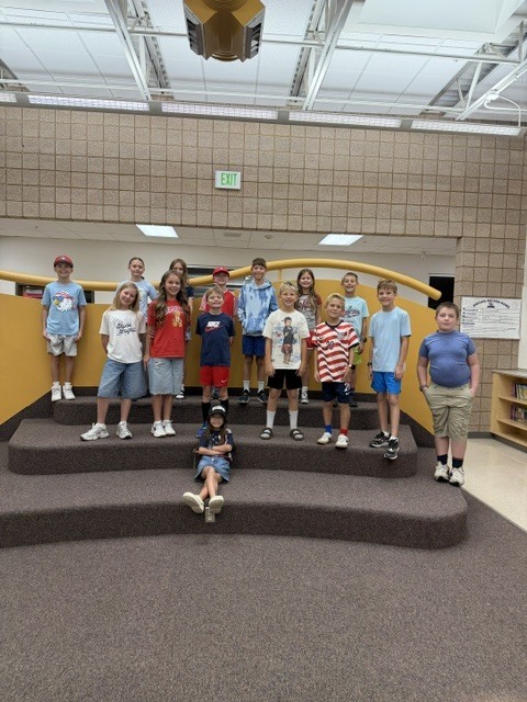 students smiling on the kiva steps wearing red white and blue