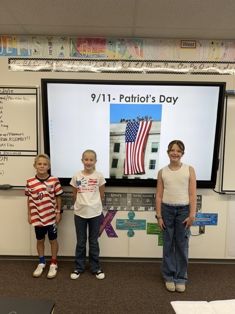 students wearing flags and red white and blue in front of a flag and writing that says 9/11- patriots day