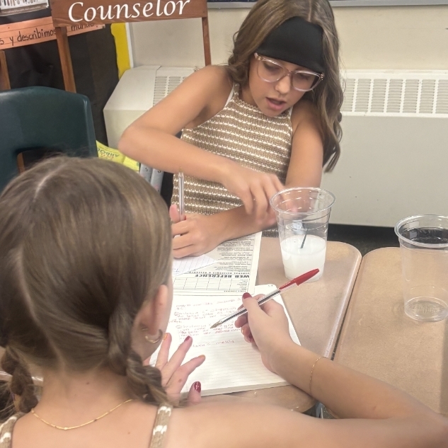 girls doing a science experiment with a beaker