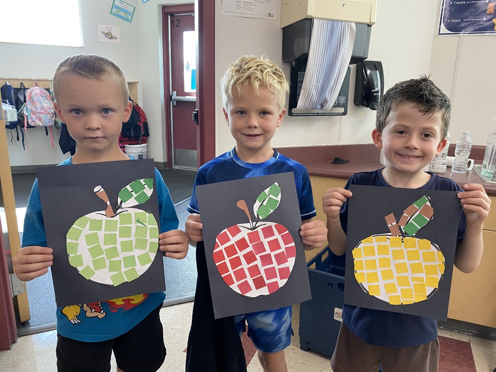 Picture of three 1st grade students holding up different apples with different colored mosaic tiles