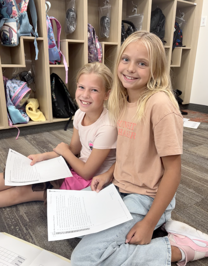 two girls holding papers and smiling