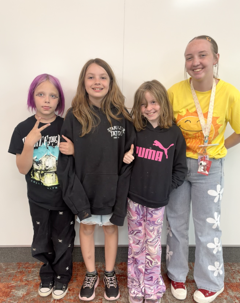 3 students standing with their teacher and smiling