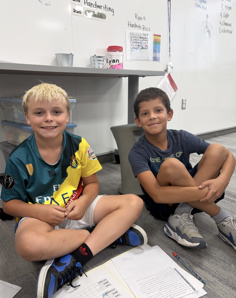 two boys sitting on the carpet smiling