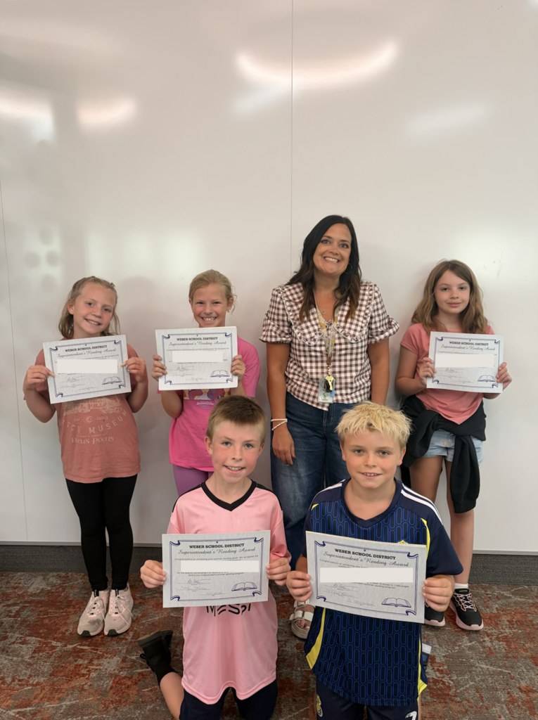 a group of students holding awards in the assembly