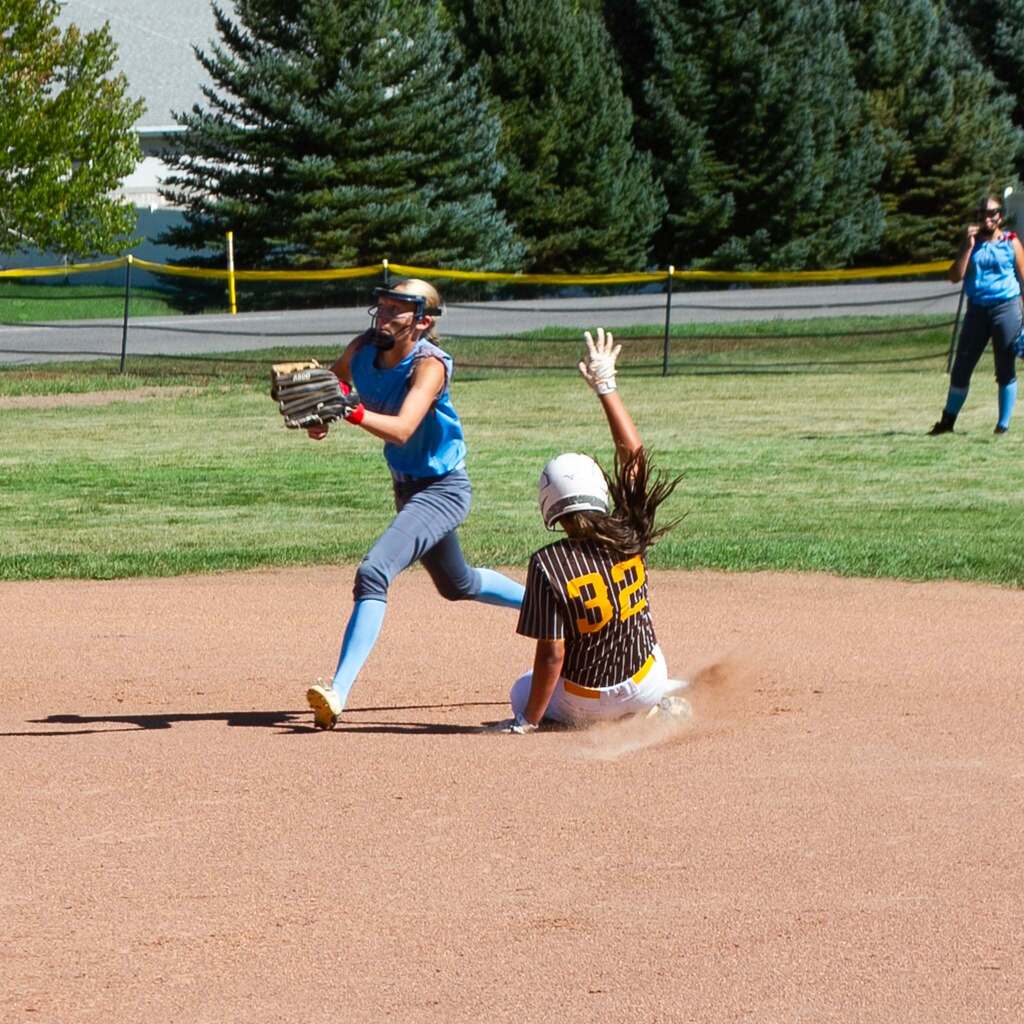 A high-energy play at second base as a Sand Ridge runner slides into the bag while a Snowcrest fielder fields the throw to attempt the tag.