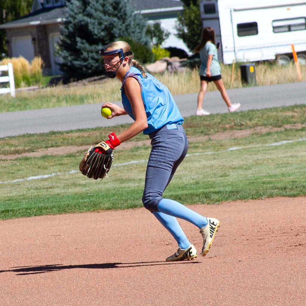 A Snowcrest softball player fields the ball on the run and prepares to make a throw across the infield.