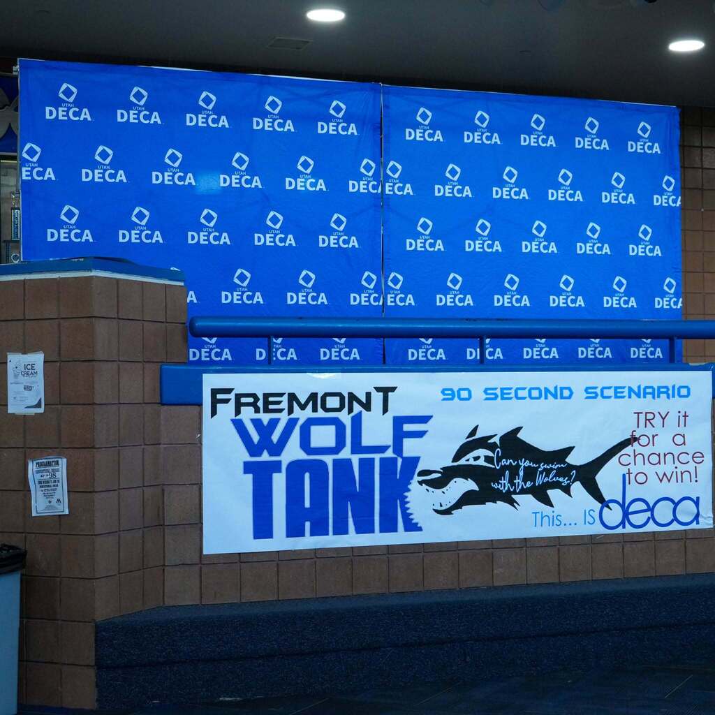 A large blue backdrop displaying repeated DECA logos alongside a banner that reads "Fremont Wolf Tank: 90 Second Scenario - Try it for a chance to win!" with a wolf silhouette.