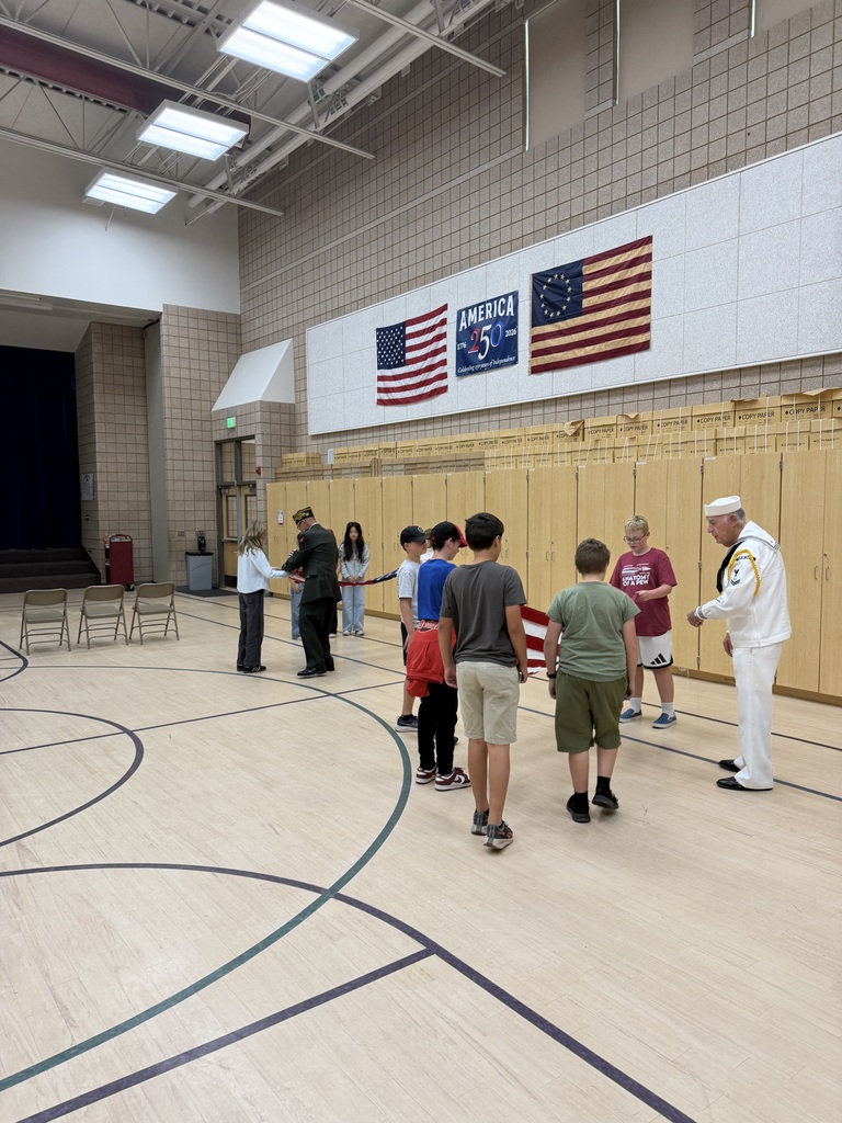 action shot of service members helping students fold the american flag