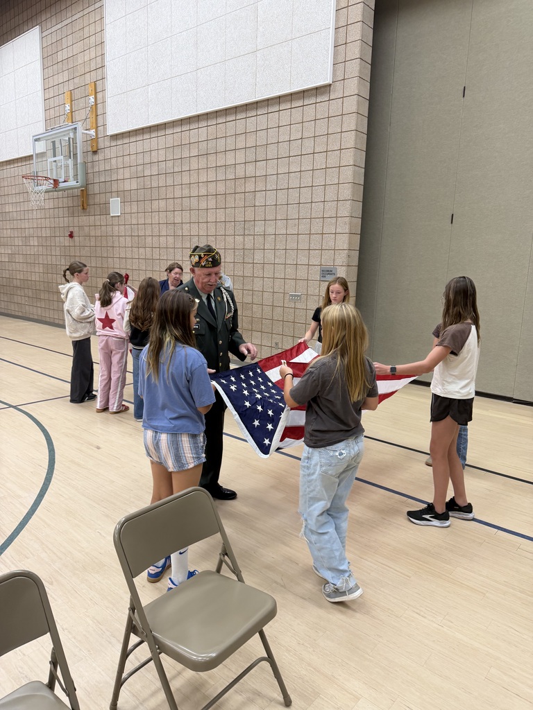action shot of service members helping students fold the american flag