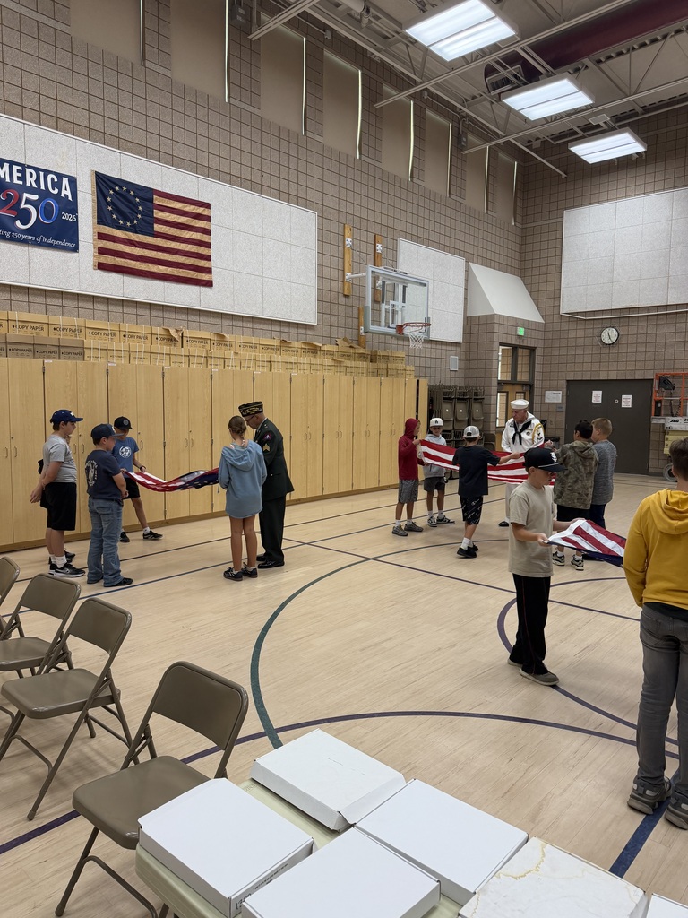 action shot of service members helping students fold the american flag