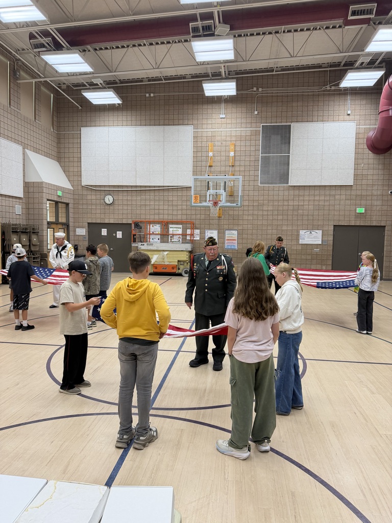 action shot of service members helping students fold the american flag