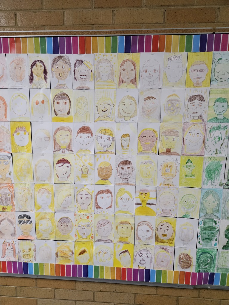 Close-up section of the bulletin board displaying self-portraits drawn in shades of yellow and light green.
