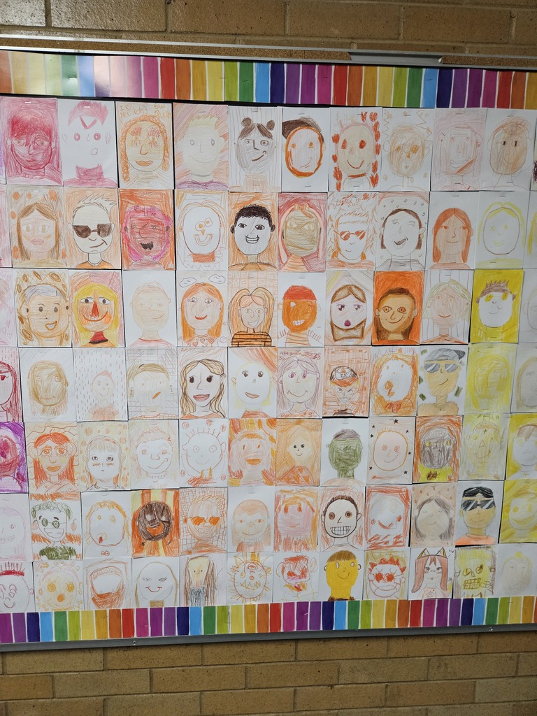 Close-up section of the bulletin board displaying self-portraits drawn in shades of orange and light yellow.