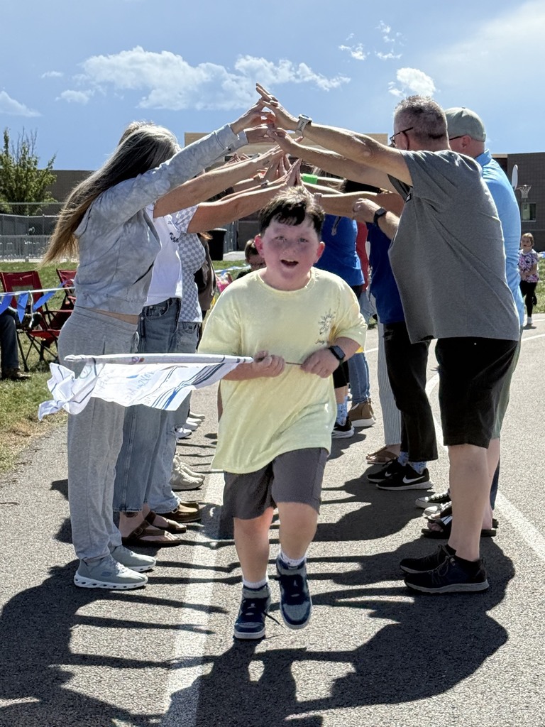 male student running under volunteers/parents/adults hands waving a white flag