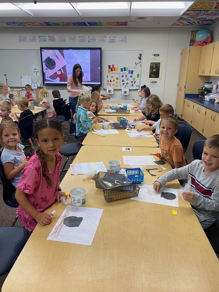 kindergarten students smiling with cauldron drawings, cutting, and actively creating art