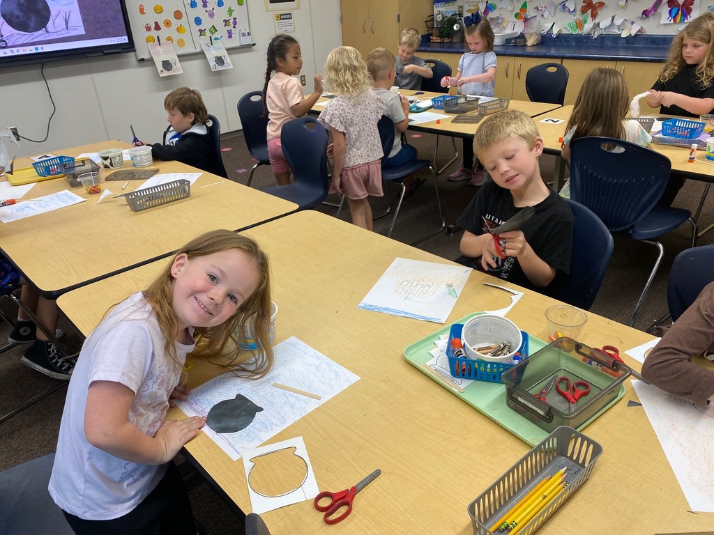 kindergarten students smiling with cauldron drawings, cutting, and actively creating art