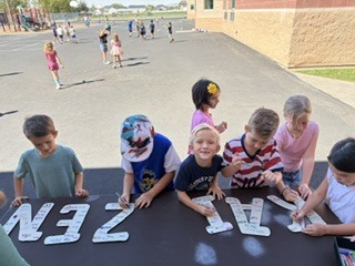group of students smiling and signing the letters KAIZEN