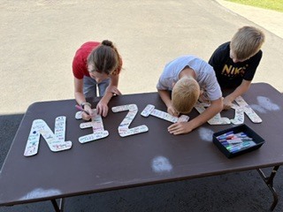 group of students smiling and signing the letters KAIZEN