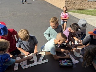 group of students smiling and signing the letters KAIZEN