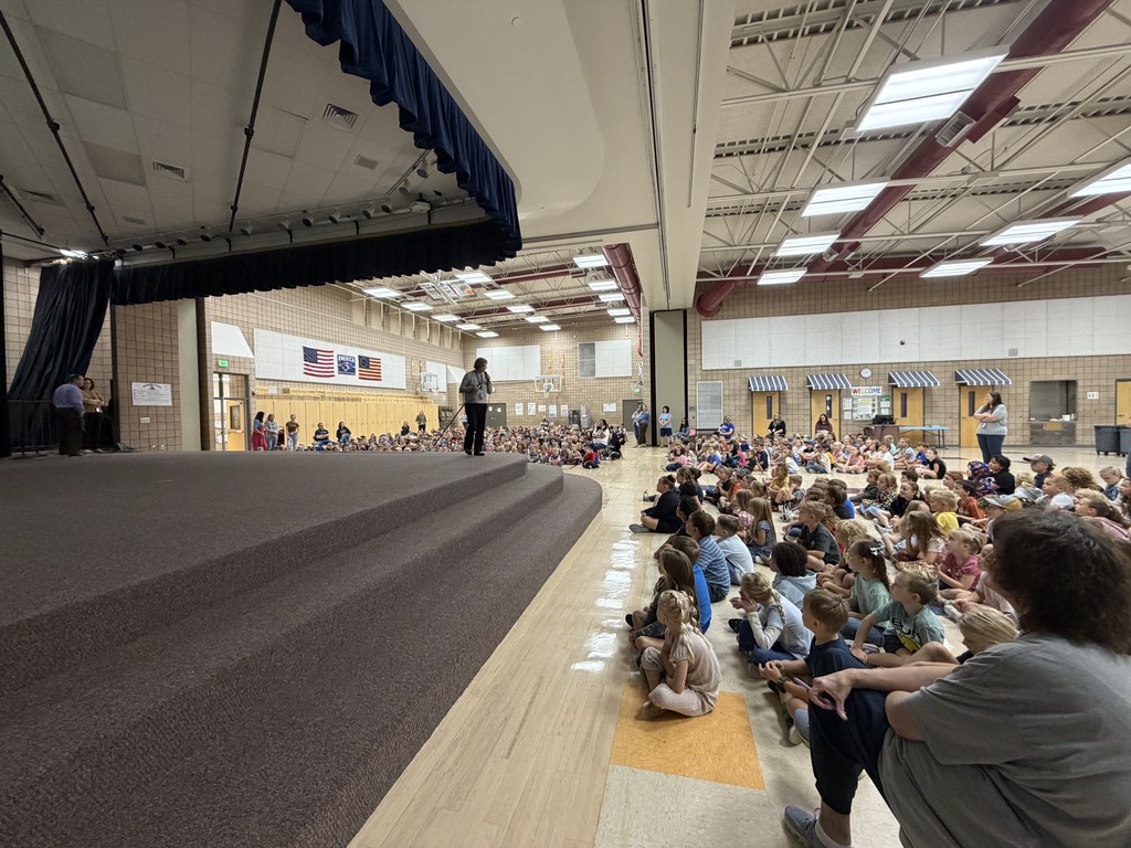superintendent reading to students, standing in front of book portrayed on the screen
