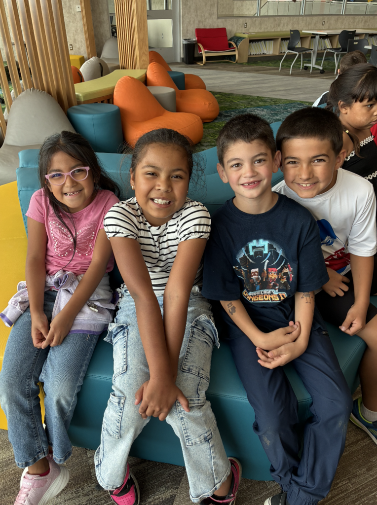 4 kids sitting on the bench in the library