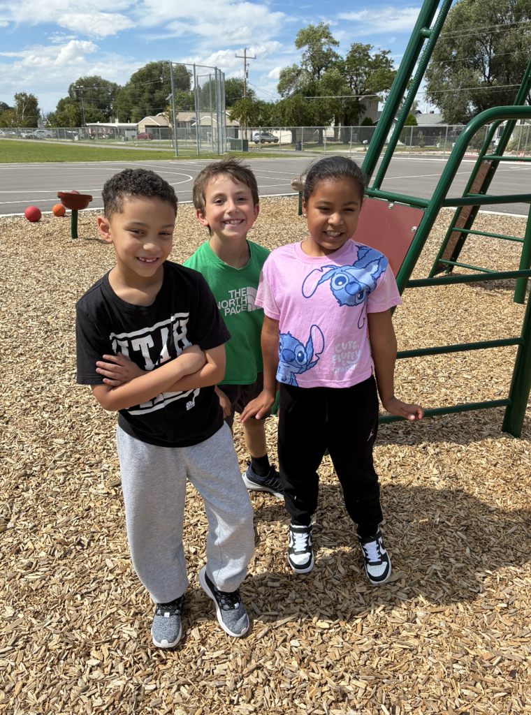3 students posing by the playground
