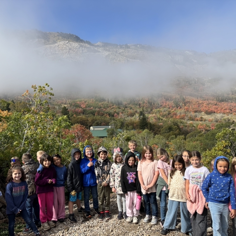 kids posing in front of a mountain with fall foliage and a bit of fog