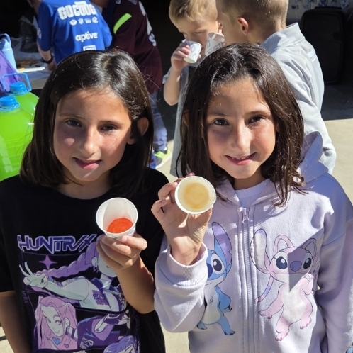 girlas holding cups with color at the bottom of the cups 