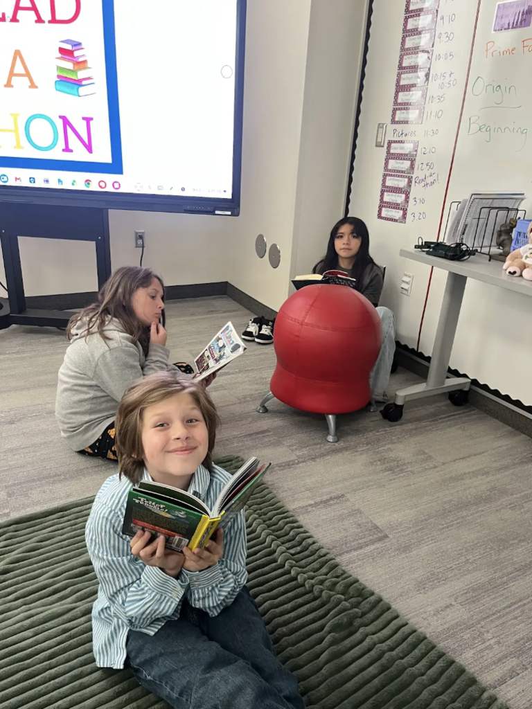 three students sitting on the floor reading