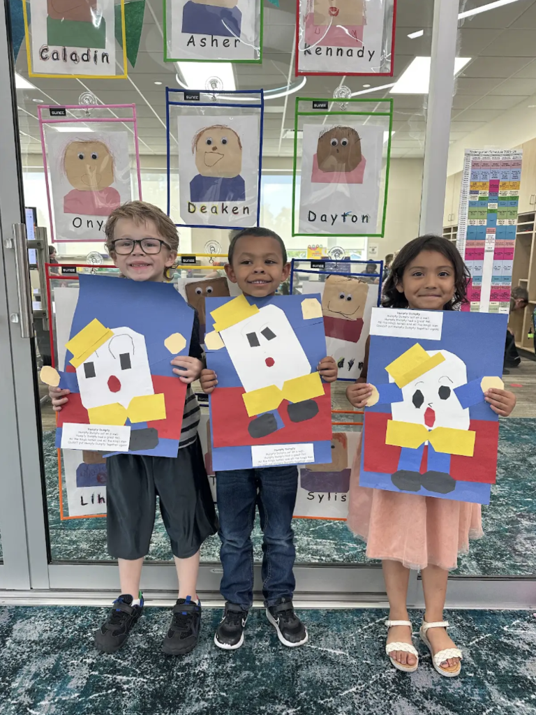 3 students holding their art projects