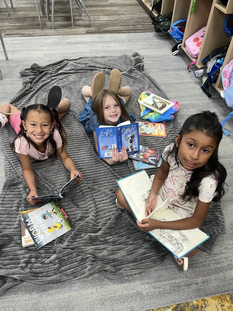 students sitting on a blanket reading