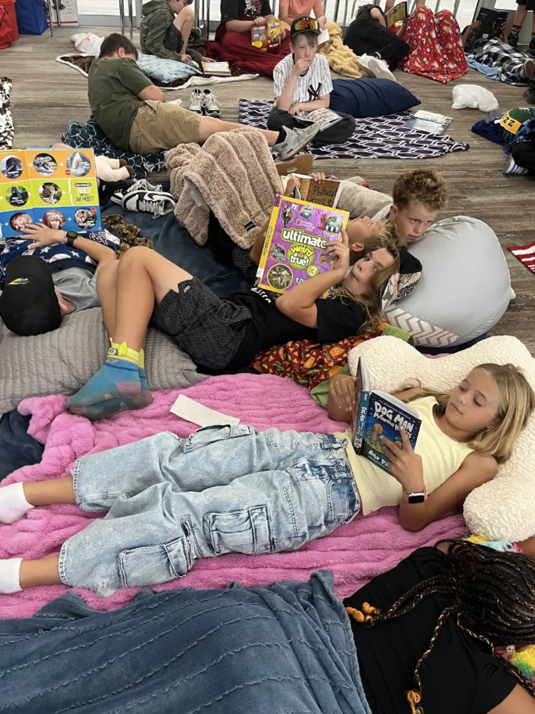 students laying on the floor with pillows and blankets reading