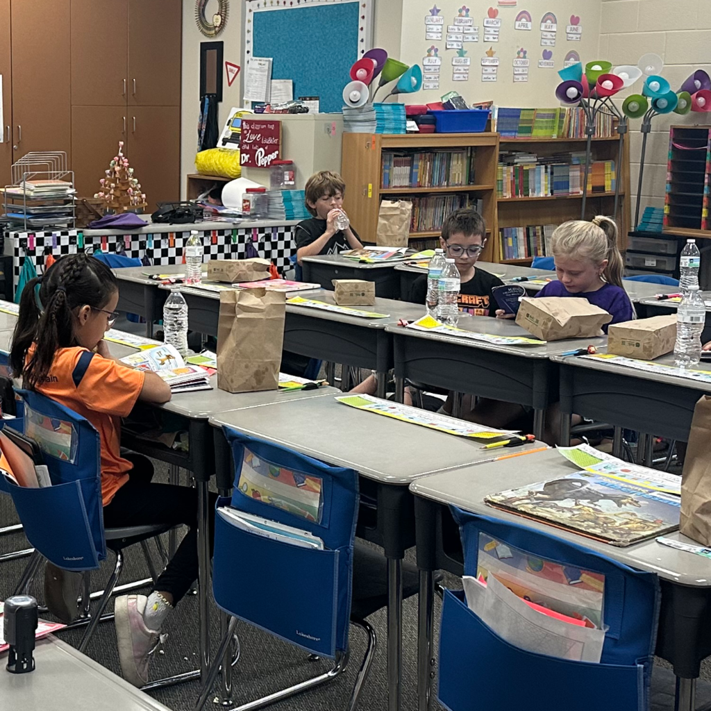 Students reading books at their desks in their classroom.