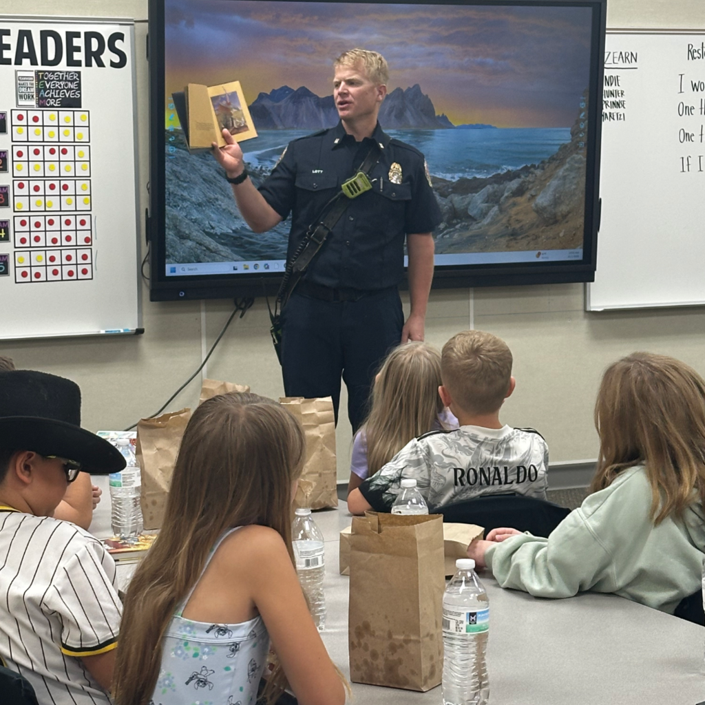 A firefighter standing in front of the class reading them a book.