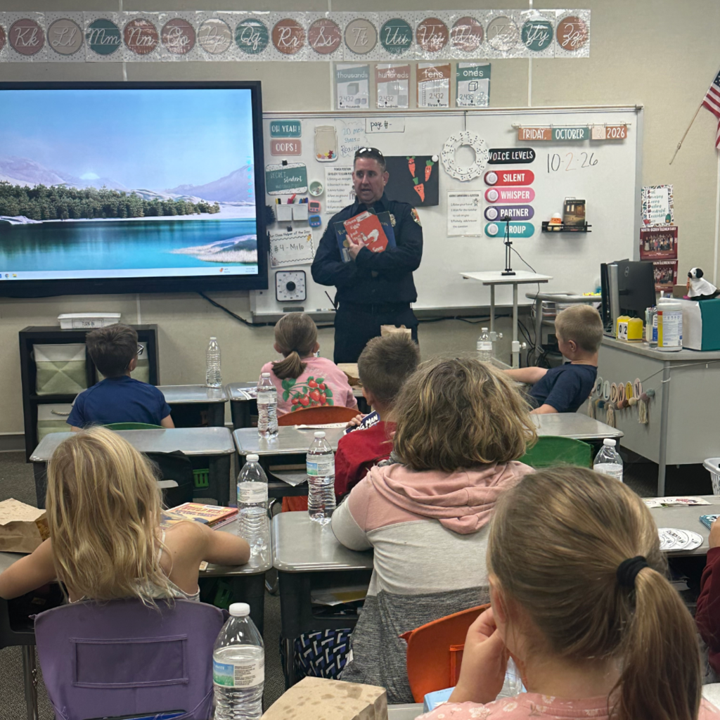 A firefighter standing in front of the class reading them a book.