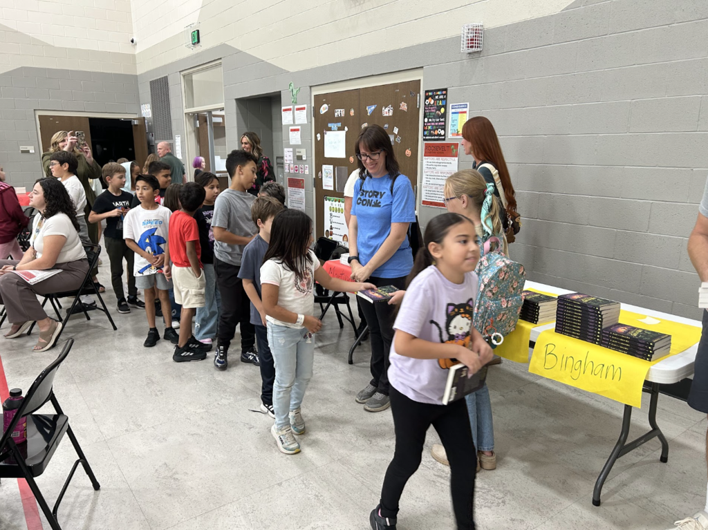 students walking in a line to receive their books