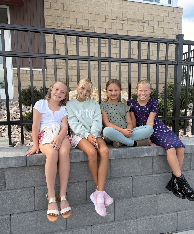 group of 4 girls sitting by a fence